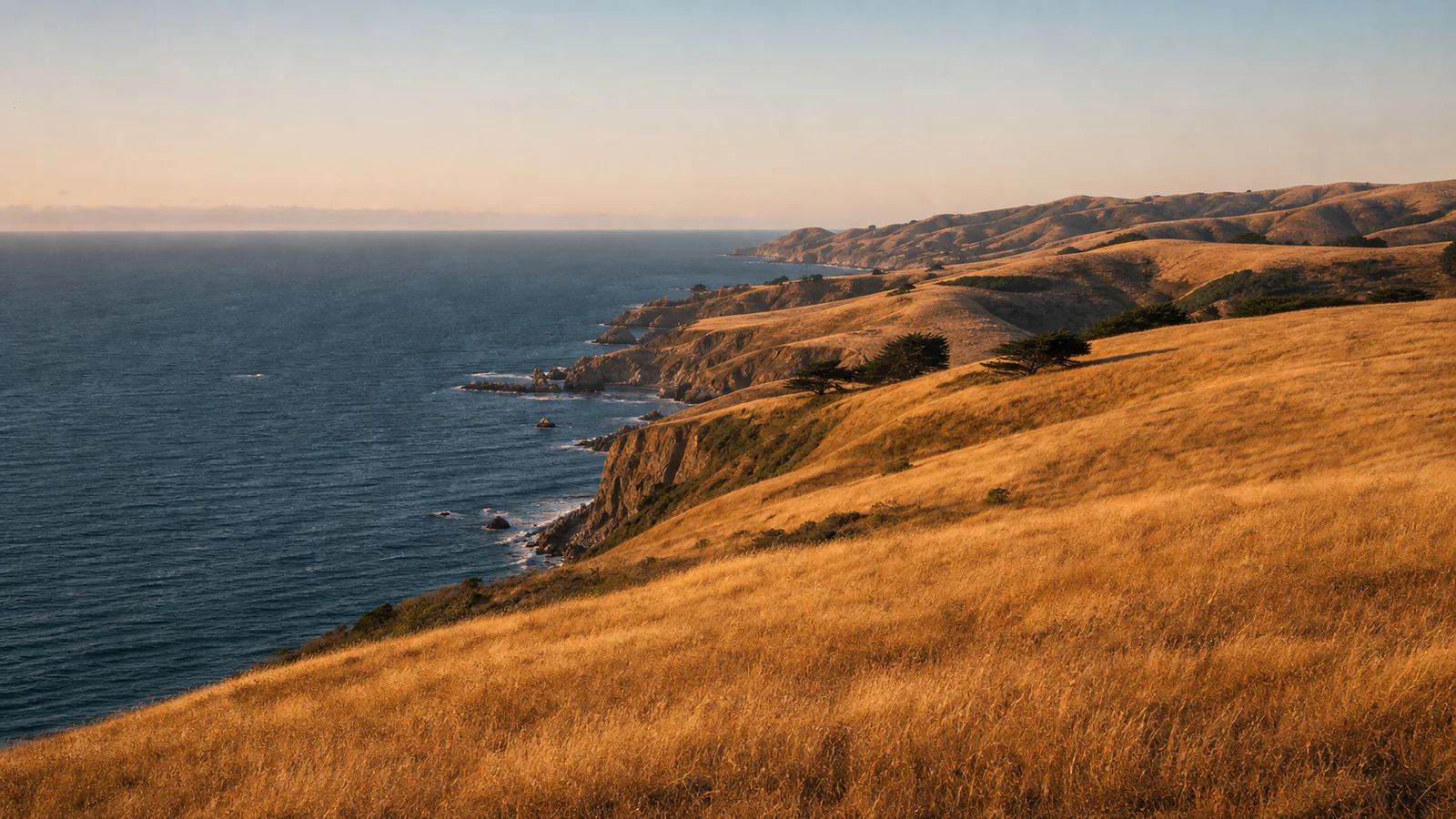 Sunlit golden hills along a California coast above the Pacific Ocean.